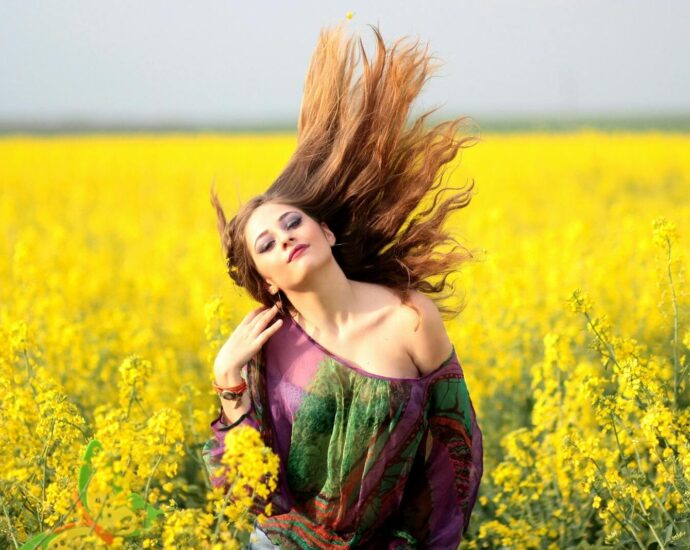 Vibrant portrait of a woman in a yellow flower field, exuding happiness and freedom.