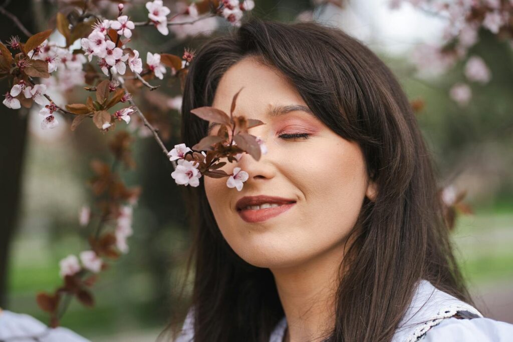 A serene portrait of a smiling woman surrounded by cherry blossoms, capturing the essence of spring.