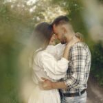 Loving couple gently embracing in a serene natural setting with lush greenery.