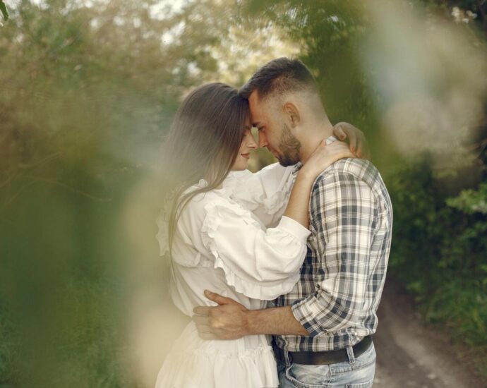 Loving couple gently embracing in a serene natural setting with lush greenery.
