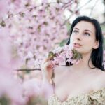 A serene portrait of a woman surrounded by cherry blossoms in a springtime setting.