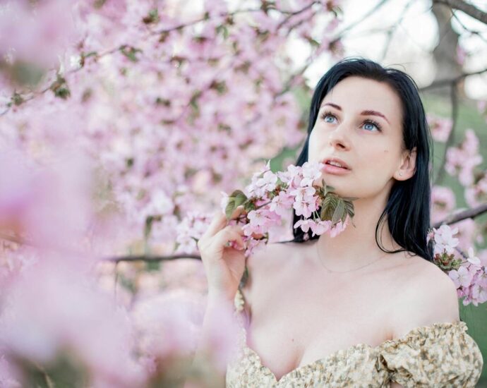 A serene portrait of a woman surrounded by cherry blossoms in a springtime setting.