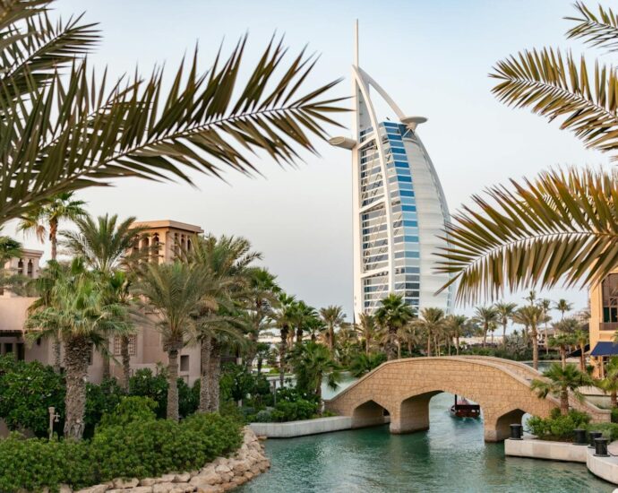 Scenic view of Burj Al Arab with surrounding palm trees and bridge in Dubai, UAE.