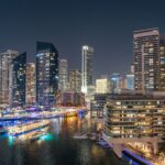 Stunning night view of Dubai Marina with illuminated skyscrapers and reflections on the water.