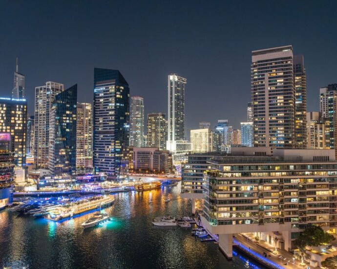 Stunning night view of Dubai Marina with illuminated skyscrapers and reflections on the water.