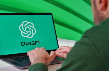 Person typing on a laptop displaying ChatGPT logo with a green vibrant setting.