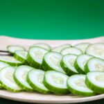 Close-up of sliced cucumbers arranged on a striped plate with a green background.