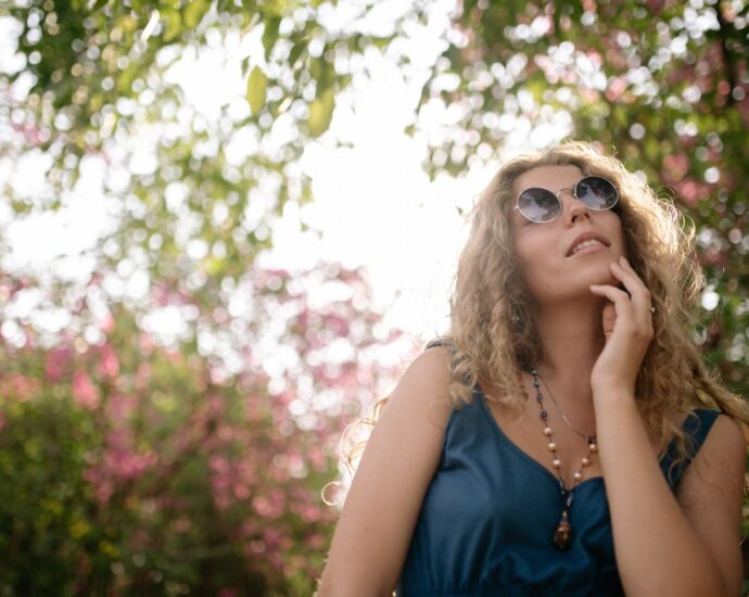 A woman in sunglasses enjoys a sunny day in a blooming garden, capturing tranquility.
