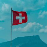red and white cross flag on pole under blue sky during daytime