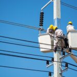 Electricians wearing safety gear work on power lines in Nakhon Ratchasima, Thailand.