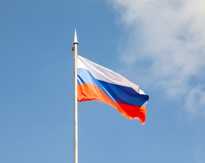 A russian flag waves against a blue sky.