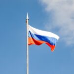The russian flag waves against a clear, blue sky.