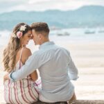 A romantic couple embraces on a scenic beach at sunset, highlighting affection and love.