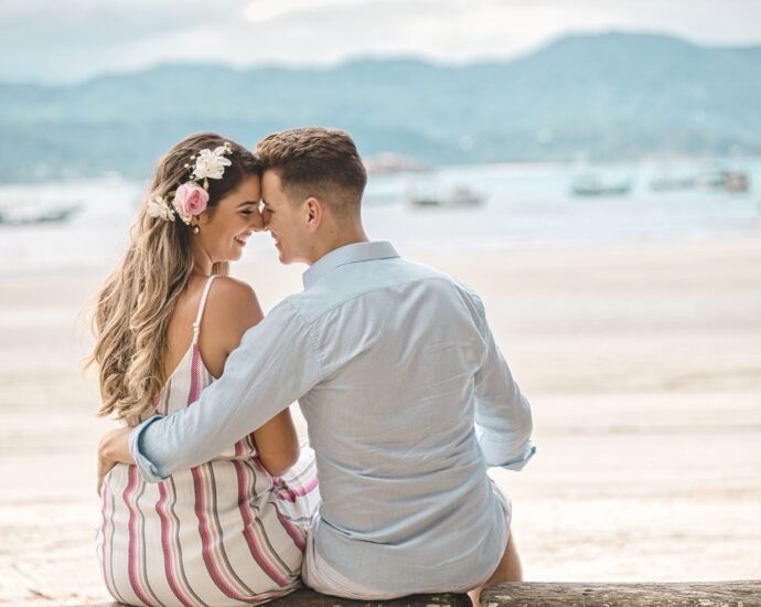 A romantic couple embraces on a scenic beach at sunset, highlighting affection and love.