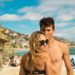woman wearing sunglasses and bikini front of man standing near seashore