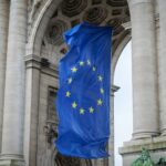 European Union flag fluttering beneath the Cinquantenaire Arch in Brussels, Belgium.