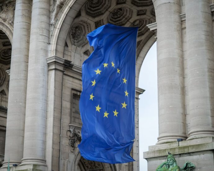 European Union flag fluttering beneath the Cinquantenaire Arch in Brussels, Belgium.