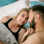 A cheerful couple cuddling in bed, showcasing love and intimacy in a home setting.