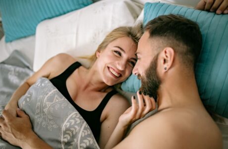 A cheerful couple cuddling in bed, showcasing love and intimacy in a home setting.