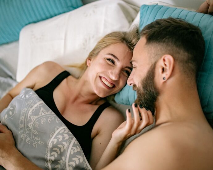 A cheerful couple cuddling in bed, showcasing love and intimacy in a home setting.