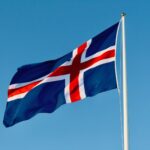 a flag flying in the wind with a blue sky in the background