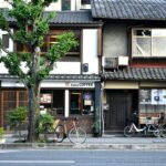 A coffee shop with a ginkgo tree and bicycles on a Japanese street