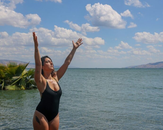 woman in black tank top standing on beach under blue sky during daytime