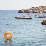 group of people swimming on body of water during daytime