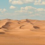 a large group of sand dunes under a blue sky