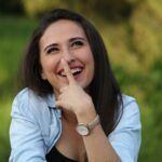 A young woman playfully touching her nose outdoors