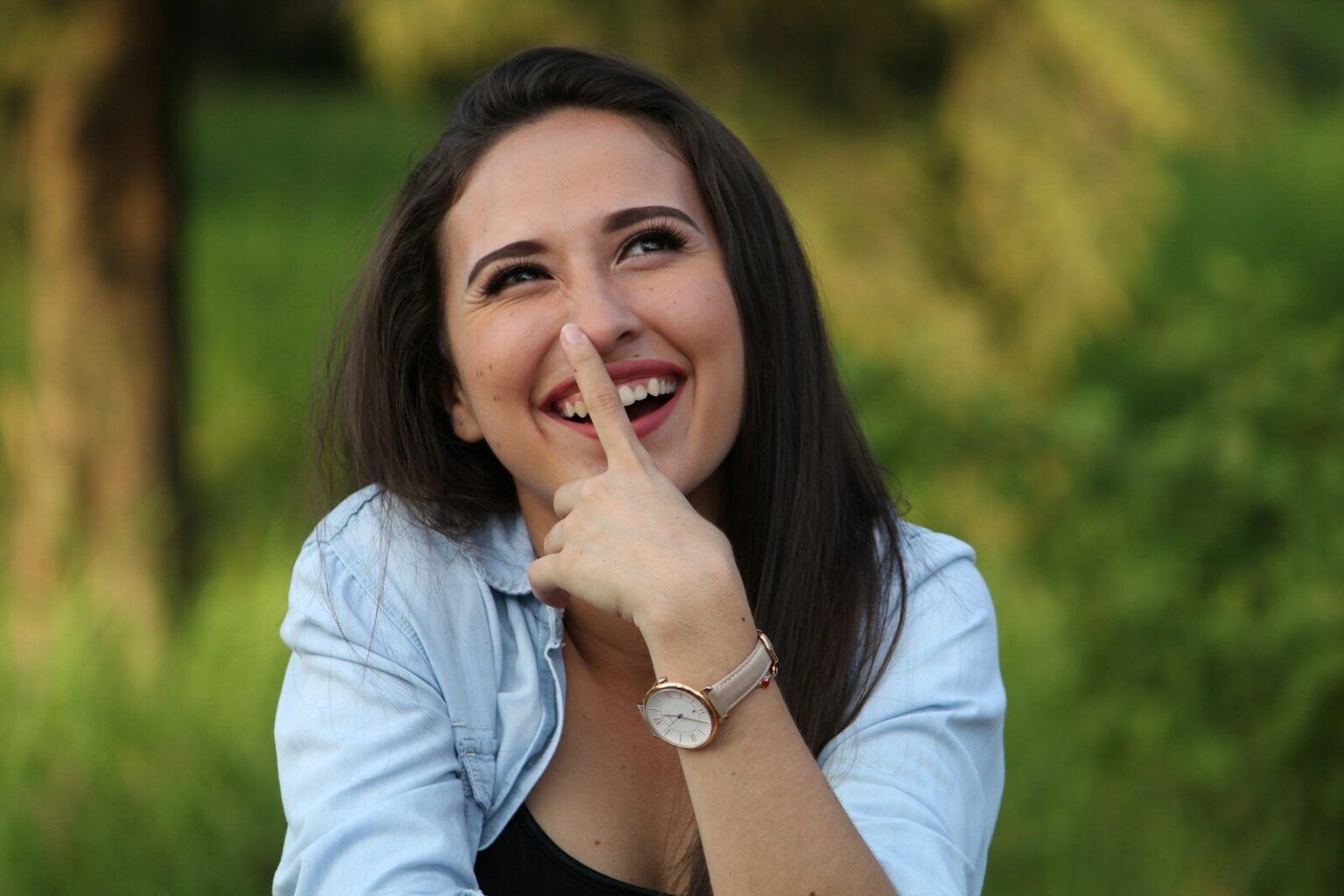 A young woman playfully touching her nose outdoors