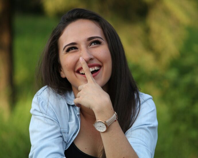 A young woman playfully touching her nose outdoors