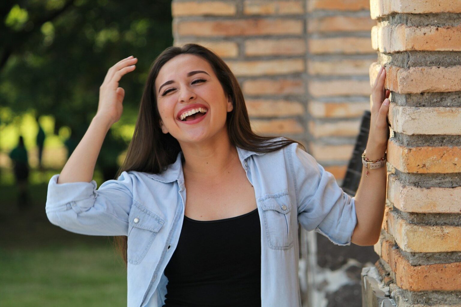 A young woman laughing with her hands in her hair