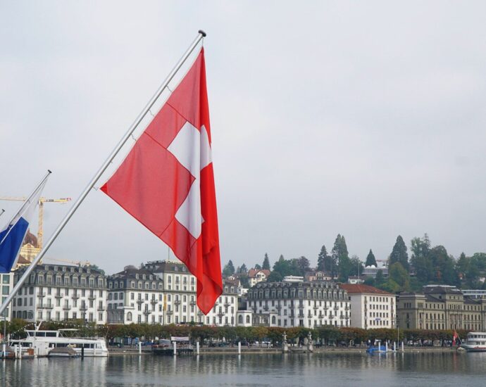 red and white flag on pole near body of water during daytime