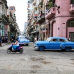 Classic blue cars and locals on a vibrant street in Havana, Cuba, showcasing the city's rich culture.