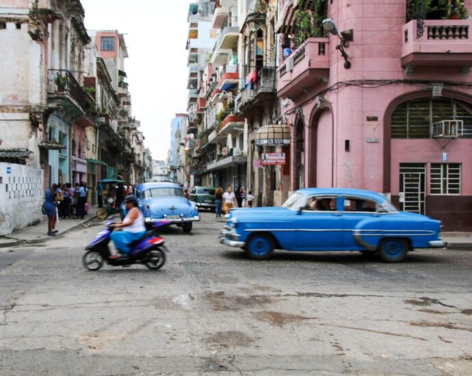 Classic blue cars and locals on a vibrant street in Havana, Cuba, showcasing the city's rich culture.