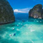 Boats on the turquoise water of Maya Bay between limestone cliffs in Thailand