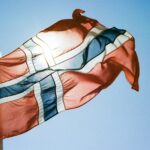 a flag flying in the wind with a blue sky in the background