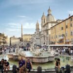 people walking and sitting near water fountain during daytime