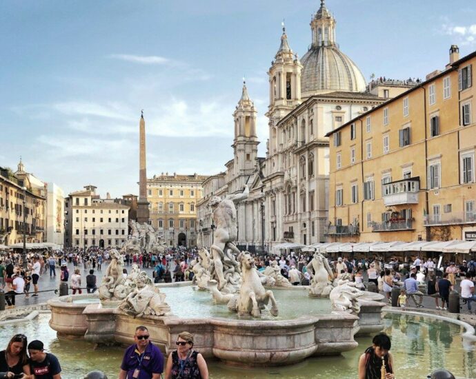 people walking and sitting near water fountain during daytime