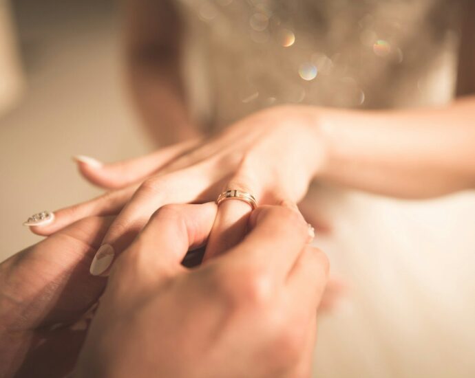 man holding gold ring on woman's finger
